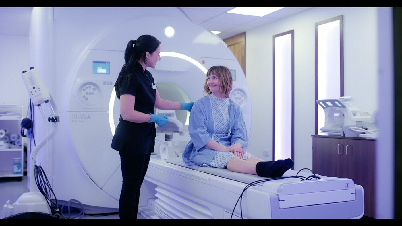 A radiology department assistant begins to position a patient for their MRI scan.