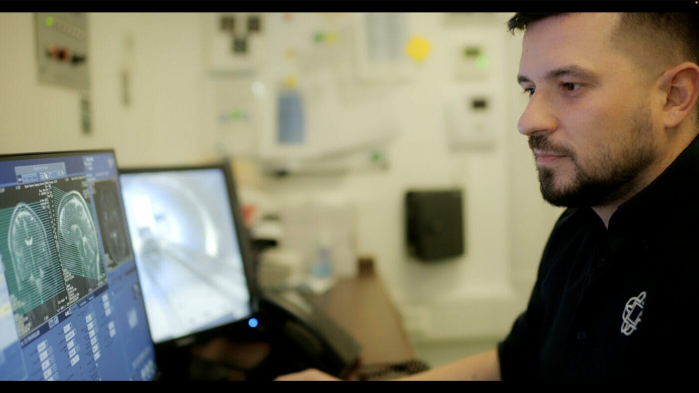 One of QSIC's radiographers plans an MRI scan from the control room.  The radiographer can see and speak to the patient at all times.