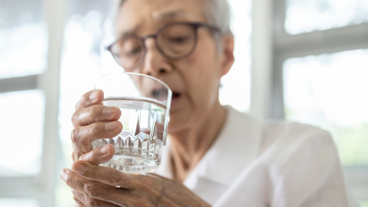 A patient with tremor supports her hand to life a cup to her mouth